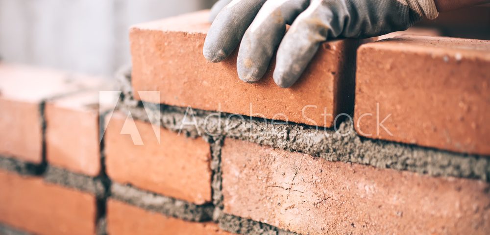 Close up of industrial bricklayer installing bricks on construction site