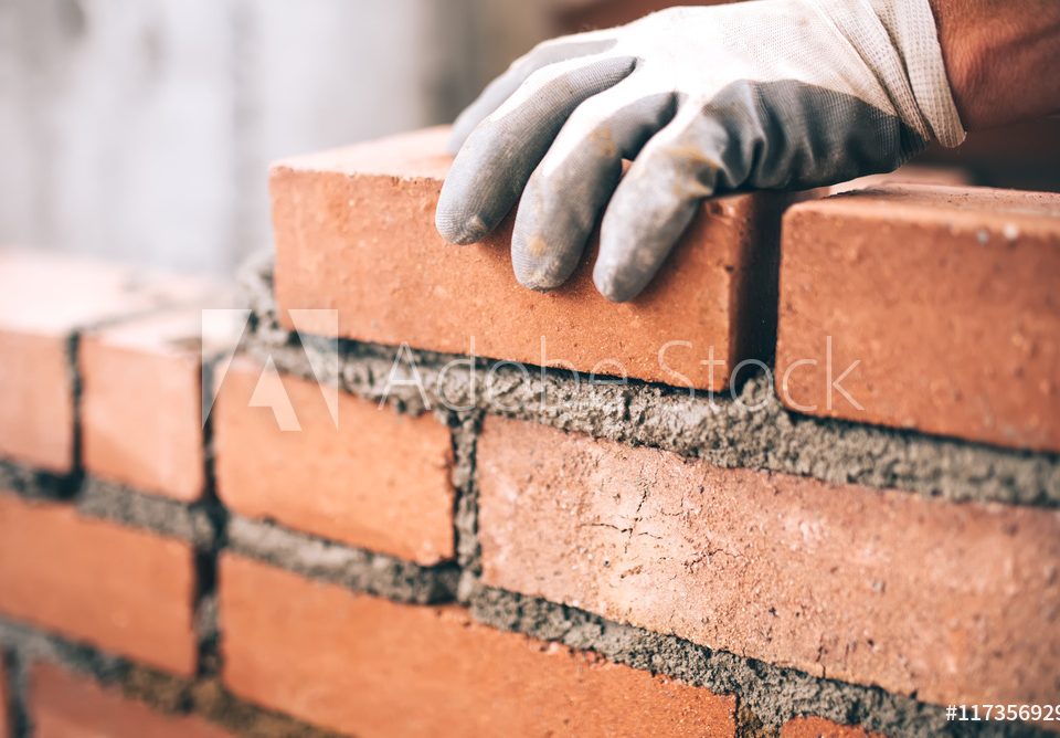 Close up of industrial bricklayer installing bricks on construction site