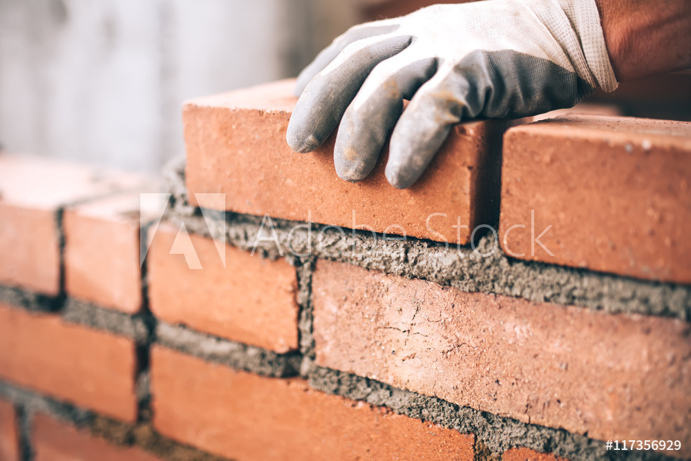 Close up of industrial bricklayer installing bricks on construction site