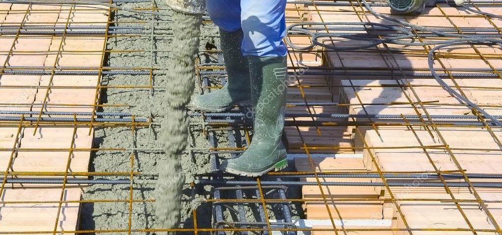 Workers pouring concrete on big floor construction