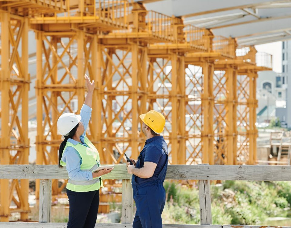 a man and a woman with ppe s talking at a construction site