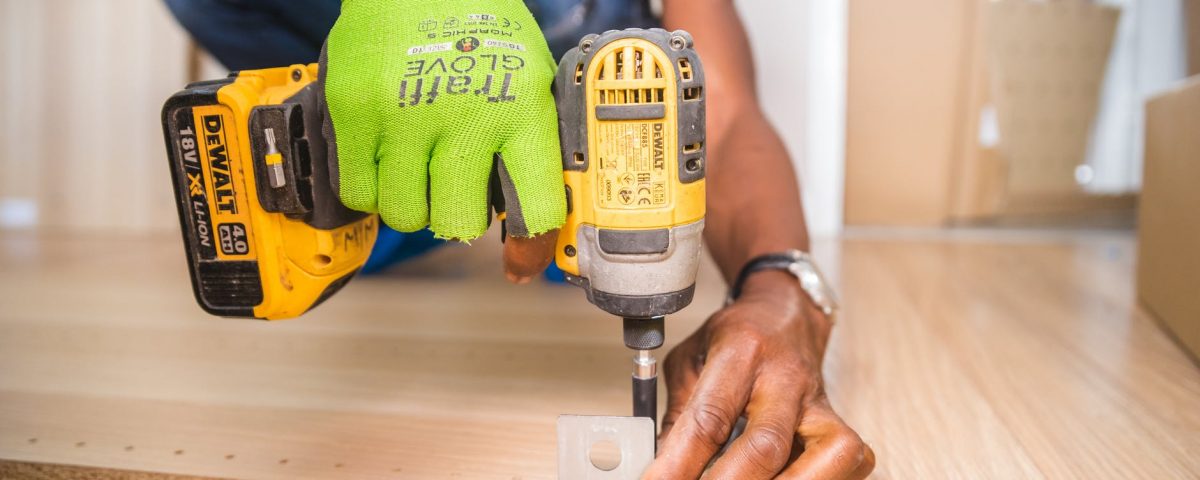 person using dewalt cordless impact driver on brown board